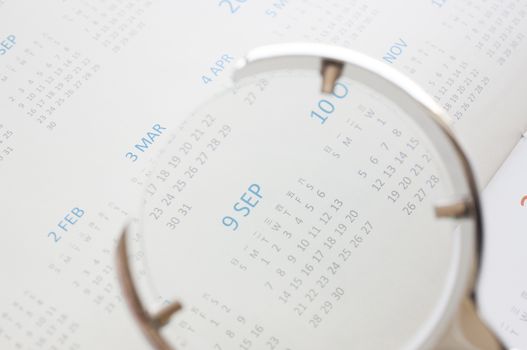 Hand holding magnifying glass to checking calendar of September