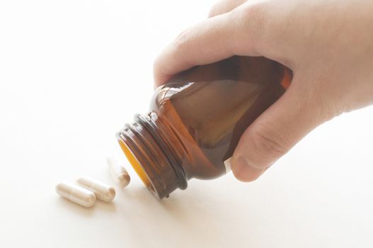 Pouring capsules from a pill bottle, focus on bottle neck