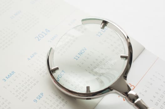 Hand holding magnifying glass to checking calendar of November