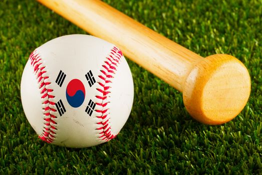 Baseball with South Korea flag and bat over a background of green grass