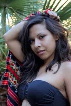 Model shot of a Hispanic beauty in front of a palm tree.