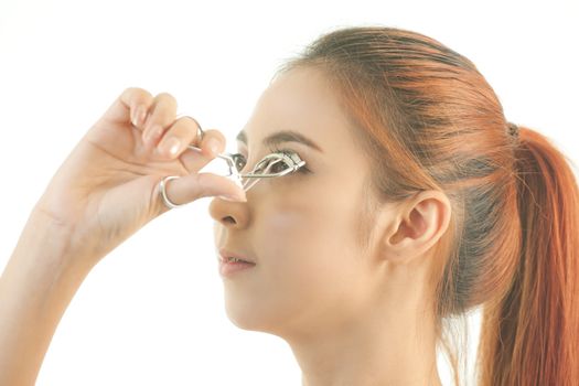 Young asian beautiful girl making her eyelashes wider with curler