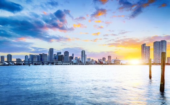 Miami city skyline panorama at dusk with urban skyscrapers over sea with reflection 