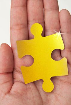 Hand holding a gold jigsaw piece 