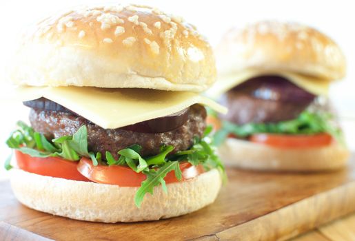 Freshly made hamburgers with tomatoes, red onion and cheese 