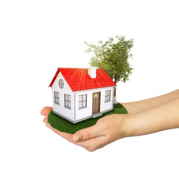 Hands holding a small house with land. Isolated on white background