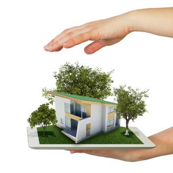 Hands holding a tablet pc and small house with land. Isolated on white background