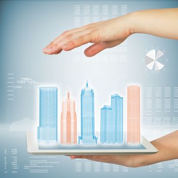 Hands holding a tablet computer. In screen tablet city of skyscrapers