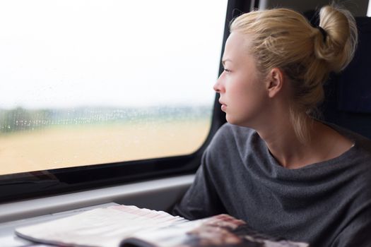 Thoughtful blonde young lady traveling by train.