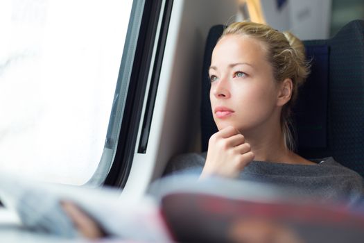 Thoughtful young lady reading while traveling by train.