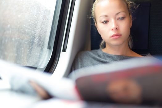 Thoughtful young lady reading while traveling by train.