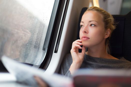 Thoughtful young lady reading while traveling by train.