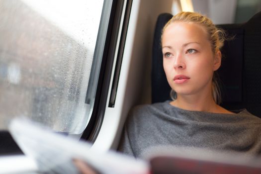 Thoughtful young lady reading while traveling by train.
