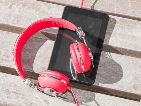 Red colored headphones and tablet PC for distance education or language course learning