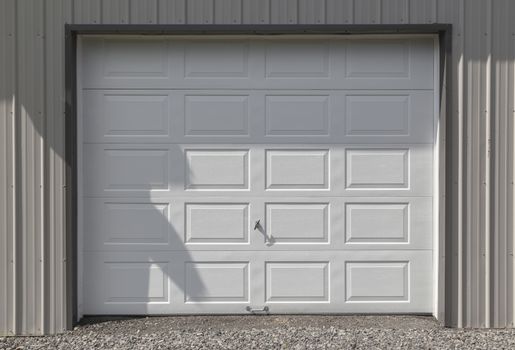 Clean and crisp white metal garage or barn door. The siding is light grey. 