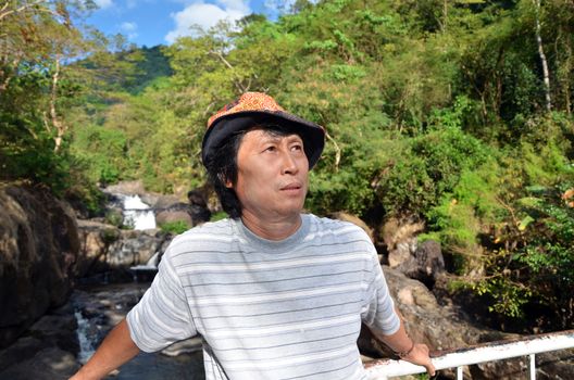 Senior man enjoying the nature with beautiful waterfall in background