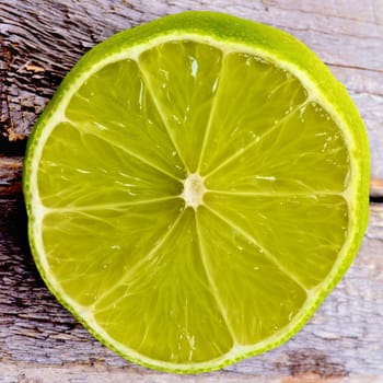 Half of Green Lime Cross Section closeup on Wooden background