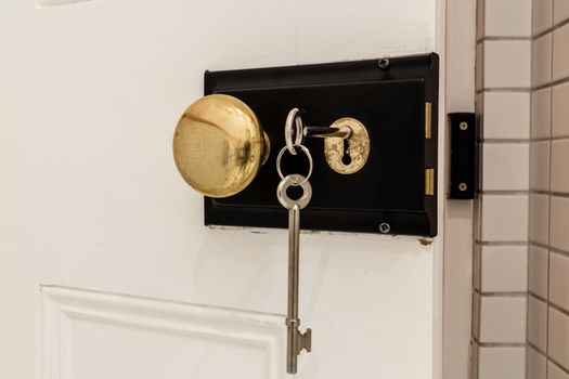 An old antique door lock with long keys and a round knob