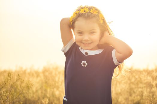 the beautiful little girl in a blue dress laughs, holds hands in long hair