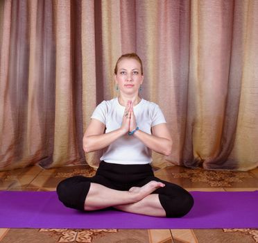 Woman yogi sitting in yoga posture on a purple mat