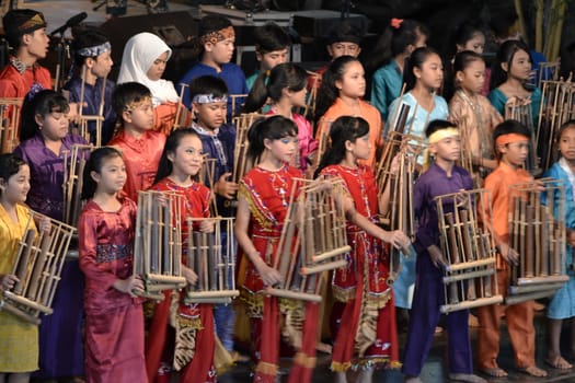 bandung, indonesia-june 16, 2014: kids playing angklung at saung angklung udjo. angklung is traditional musical heritage made from bamboo and worldwide recognize originally from indonesia.