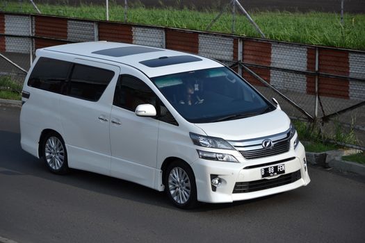 bandung, indonesia-june 16, 2014: white colored toyota vellfire cruising on the road.