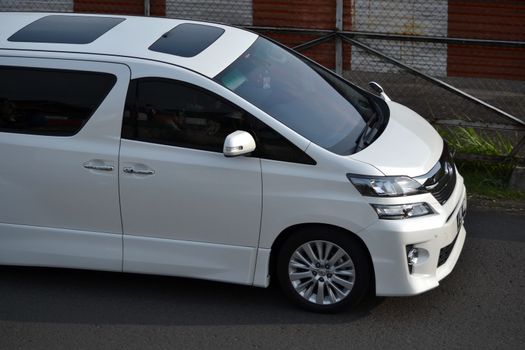 bandung, indonesia-june 16, 2014: white colored toyota vellfire cruising on the road.