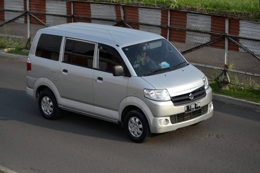 bandung, indonesia-june 16, 2014: silver colored suzuki APV cruising on the road.