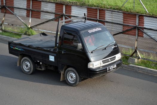 bandung, indonesia-june 16, 2014: black colored suzuki carry cruising on the road.