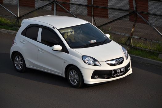 bandung, indonesia-june 16, 2014: white colored honda brio cruising on the road.