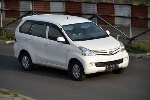 bandung, indonesia-june 16, 2014: white colored toyota avanza cruising on the road.