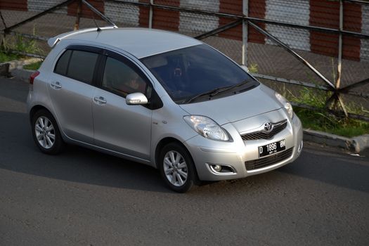 bandung, indonesia-june 16, 2014: silver colored toyota yaris cruising on the road.