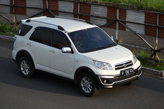 bandung, indonesia-june 16, 2014: white colored daihatsu terios cruising on the road.