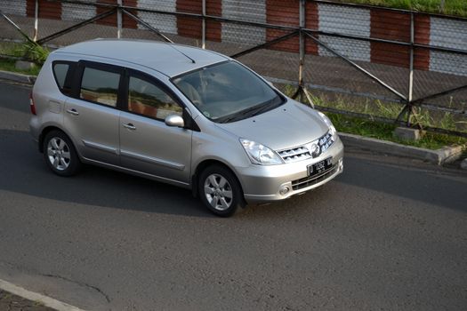 bandung, indonesia-june 16, 2014: silver colored nissan grand livina cruising on the road.