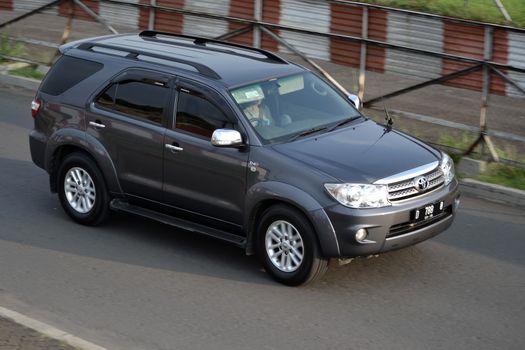 bandung, indonesia-june 16, 2014: grey colored toyota fortuner cruising on the road.
