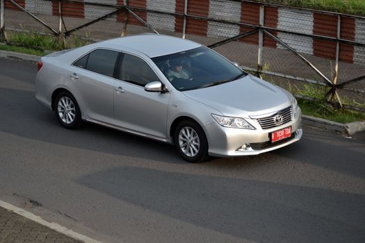 bandung, indonesia-june 16, 2014: silver colored toyota camry cruising on the road.