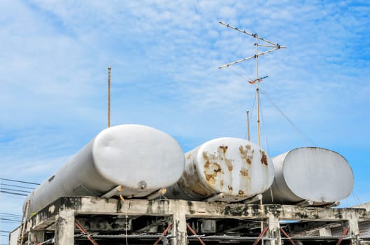 Three water tanks under  blue sky with clouds