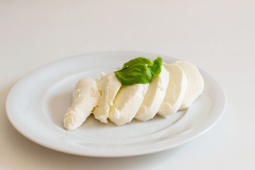 Slices of italian mozzarella with leaves of basil