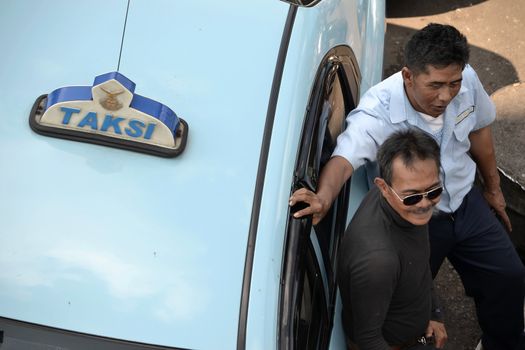 bandung, indonesia-june 16, 2014: taxi driver get chill out for a while after working hours.