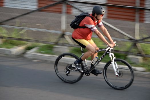 bandung, indonesia-june 16, 2014: man with backpack are riding bicycle in the afternoon.