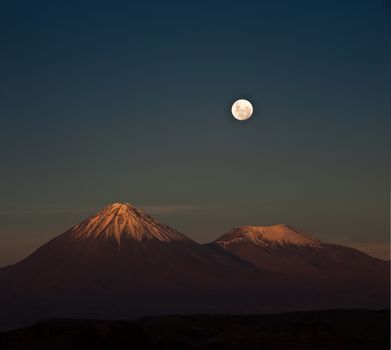 Full-moon in the Moon Valley. Volcanoes Licancabur and Juriques, west of San Pedro de Atacama, Chile in the Cordillera de la Sal, in the Atacama desert of Chile