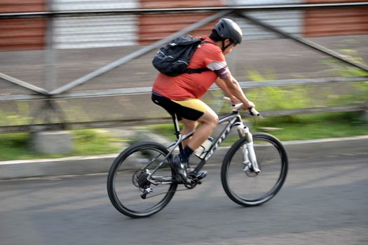 bandung, indonesia-june 16, 2014: man with backpack are riding bicycle in the afternoon.