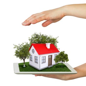 Hands holding a tablet pc and small house with land. Isolated on white background