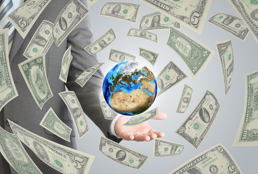 Businessman in a suit holding a earth. Money falling around