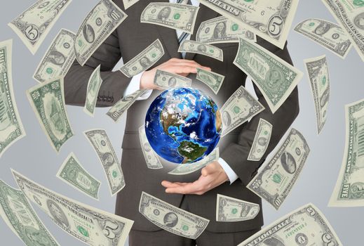 Businessman in a suit holding a earth. Money falling around