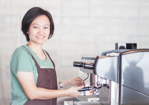 Asian barista smiling and making cup of coffee, stock photo