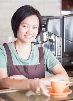 Smiling asian barista   posing with cup of coffee, stock photo