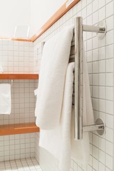 Two white bath towels hanging on a silver towel rack