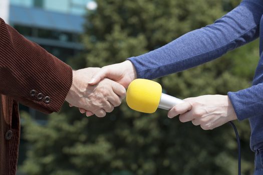 Businessman and a female reporter shaking hands before media interview