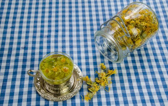 organic healing rural marigold tea cup and glass jar with dried flowers on the table